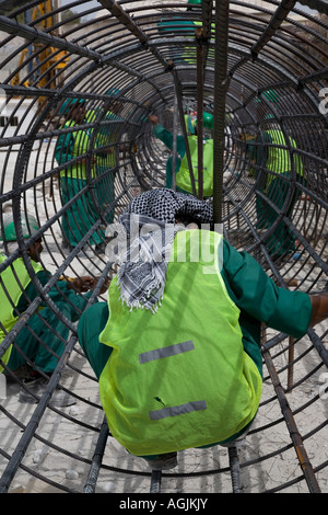 Lavoratori preparazione rebar gabbia circolare telaio per cemento armato foundation posa su un sito di costruzione ad Abu Dhabi Foto Stock