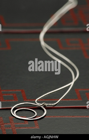 Collana fatta di due fatti a mano in argento sterling ring posti su una casella. Foto Stock