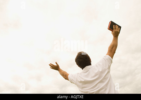 Uomo con la Bibbia con i bracci aperti Foto Stock