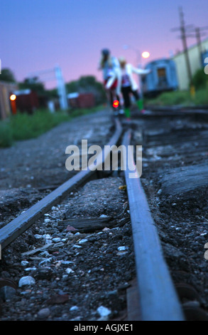 Due ragazze adolescenti a piedi lungo i binari della ferrovia al crepuscolo e Santa Fe, New Mexico, USA, America del Nord Foto Stock