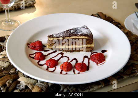 Dessert tiramisù su un piatto bianco, con fragole e salsa al cioccolato, in un ristorante Foto Stock