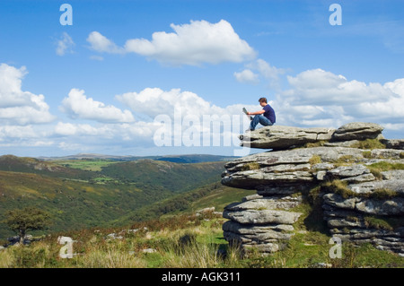 Giovane uomo seduto su di una roccia leggendo una rivista REGNO UNITO Foto Stock