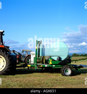 Balle rotonde essendo avvolto utilizzando un trattore e attrezzatura di insilato in Carmarthenshire Wales UK Foto Stock