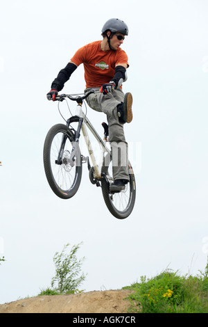 Giovane uomo jumping con la sua mountain bike su una pista sterrata Foto Stock