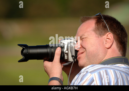 Un fotografo dilettante che usa la fotocamera Nikon strinza il viso per quell'importante scatto. Foto Stock