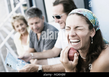 Metà donna adulta in possesso di un Apple con i suoi amici seduto accanto a lei Foto Stock