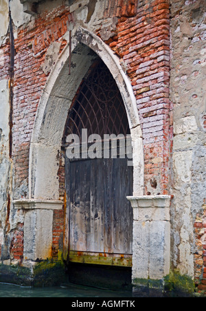 Vecchia porta di legno, apertura direttamente su un piccolo canale, Venezia, Italia Foto Stock