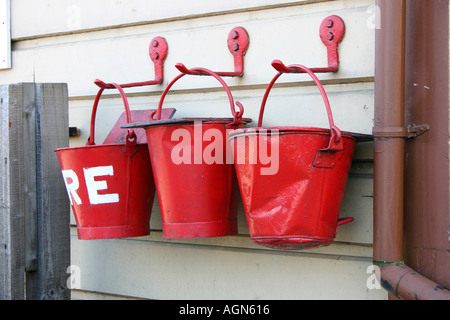 Tre red fire bucket appeso a una parete Foto Stock