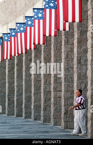 Turista nella bandiera americana shirt camminare sotto bandiere nordamericane a Mount Rushmore National Memorial National Park Service Foto Stock