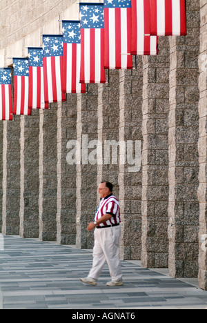 Turista nella bandiera americana shirt camminare sotto bandiere nordamericane a Mount Rushmore National Memorial National Park Service Foto Stock