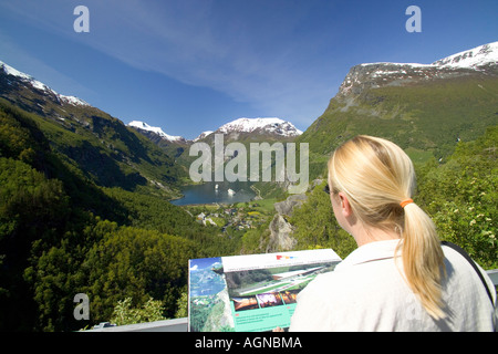 Donna di assorbire la vista panoramica del Geirangerfjord da un punto di vista collina Geiranger Norvegia Foto Stock