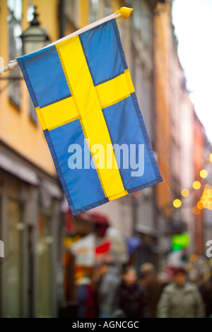 Bandiera svedese appesi lungo Vasterlangssgatan Gamla Stan più popolare via dello shopping a Stoccolma Svezia Foto Stock