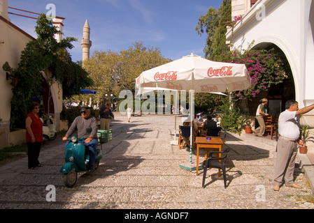 dh KOS CITTÀ GRECIA KOS Cafe tavoli uomo su moto aereo albero di Ippocrate Platanou Piazza taverna greca tavolo Foto Stock