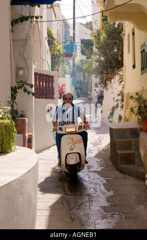 Dh MANDRAKI Grecia NISSIROS uomo su scooter bici del motore guida lungo strada stretta viuzza Foto Stock