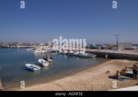 Dh Kamari Kamari Bay Grecia KOS famiglie di turisti sulla spiaggia accanto al molo barche ancorate nella baia Foto Stock