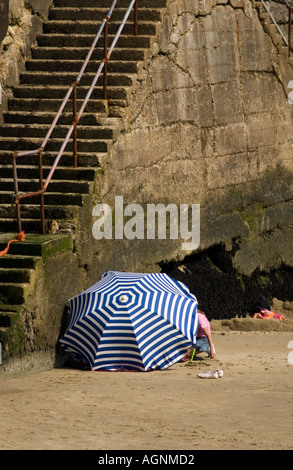 Turisti sotto un ombrello su una spiaggia del Regno Unito Foto Stock