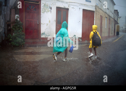 Basseterre St Kitts bambini sulla strada di ritorno da scuola acquazzone tropicale Foto Stock