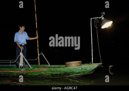 Cina Guangxi Yangshuo un cormorano Pescatore sul fiume Li Jiang dimostrando il suo lavoro per i turisti di notte Foto Stock