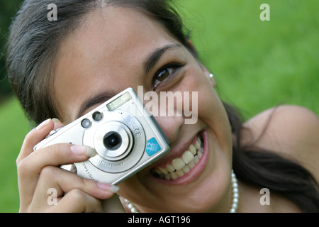 Ritratto di un sorridente giovane donna che guarda verso l'alto utilizzando una fotocamera digitale Foto Stock
