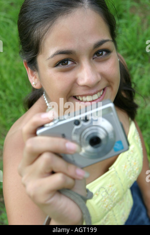 Ritratto di un sorridente giovane donna che guarda verso l'alto utilizzando una fotocamera digitale Foto Stock