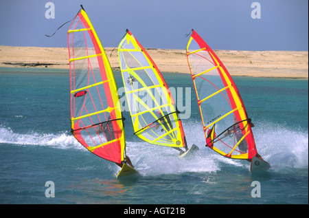 Tre windsurfisti gybe (ruotare) Chiudere insieme in un gruppo sul Mar Rosso in Ras Sudr Sinai Egitto sotto il sole con una spiaggia di sabbia in background Foto Stock