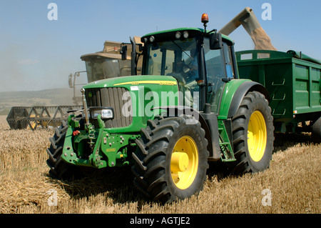 Trattore John Deere rimorchio e New Holland TX68 plus combinare la raccolta di grano maturo lo scarico del raccolto Foto Stock