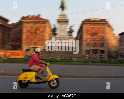 In rapido movimento di giallo scooter Vespa nel cerchio di traffico con il monumento a Garibaldi Milano Italia Foto Stock