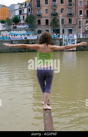 Bilanciamento di donna con le braccia aperte su un palo grassa oltre il fiume Nervion durante la Cucaña fiesta Bilbao Basque Country Spagna Foto Stock