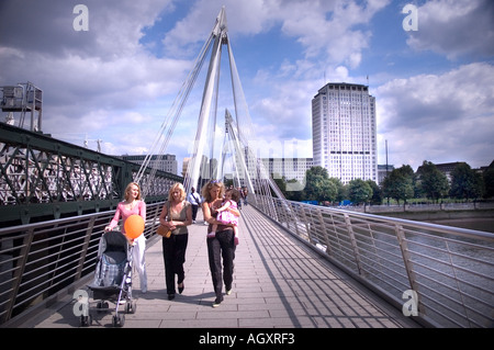 Tre donne con un bambino a camminare su un ponte, il Golden Jubilee ponti sul fiume Tamigi a Londra, Inghilterra Foto Stock