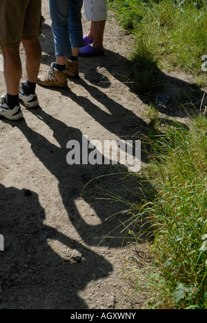 Le ombre delle persone e le spalle delle loro gambe per una passeggiata su una luminosa giornata d'estate Foto Stock