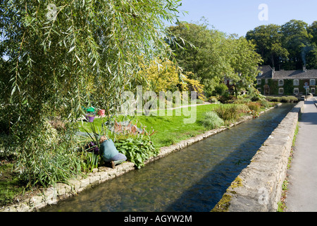 Un giardiniere tendendo i motivi di Bibury allevamento di trote accanto al Fiume Coln nel villaggio Costwold di Bibury, Gloucestershire Foto Stock