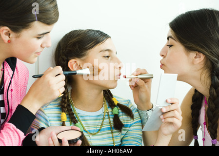 Due giovani amici di sesso femminile mettendo il make-up sul più giovane ragazza Foto Stock