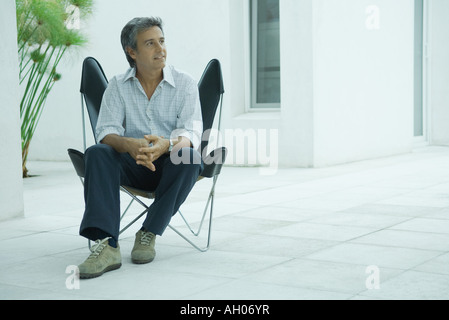 Coppia uomo seduto in poltrona, sorridente, a piena lunghezza Foto Stock