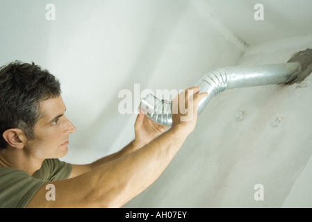 Uomo di installare il condotto dell'aria Foto Stock