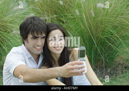 Coppia giovane in posa mentre l uomo può contenere fino telefono cellulare per scattare la foto Foto Stock