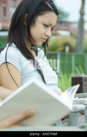 Giovane donna, libro in primo piano sfocato Foto Stock