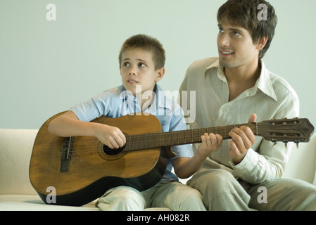 Uomo ragazzo di insegnare a suonare la chitarra Foto Stock