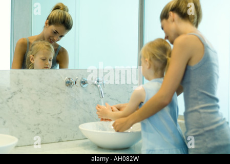 Donna aiutando bambina di lavare le mani nel lavandino del bagno Foto Stock