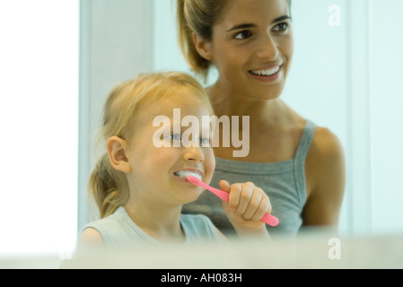 Donna aiutando bambina spazzola denti Foto Stock