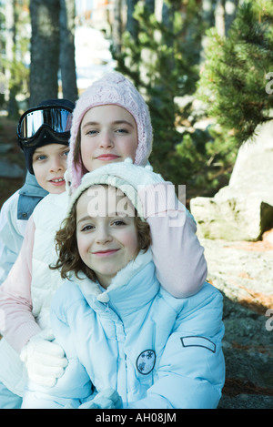 Teen girl preteen con un ragazzo e una ragazza, indossando cappotti invernali e cappelli, ritratto Foto Stock