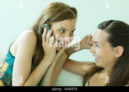 Due giovani amici sorridente ad ogni altro, uno tramite telefono cellulare Foto Stock