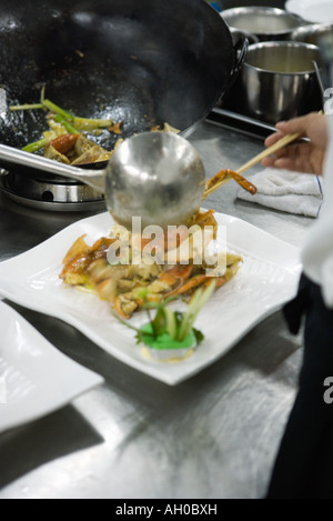 Lo Chef medicazione piastre in cucina commerciale Foto Stock