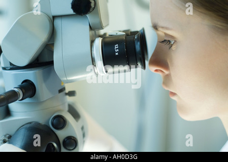 Giovane donna usando microscopio Foto Stock