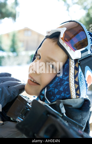 Ragazzo tenendo gli sci in spalla, sorridente in telecamera, close-up Foto Stock