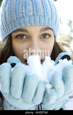 Ragazza adolescente di mangiare la neve fuori delle mani, guardando la fotocamera Foto Stock