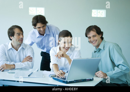 Quattro soci di affari con computer portatile, sorridente Foto Stock