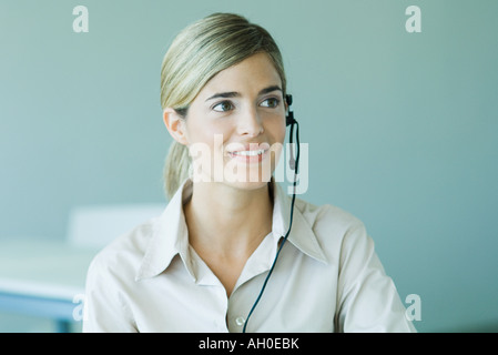 Giovane imprenditrice che indossa la cuffia, sorridente, testa e spalle Foto Stock