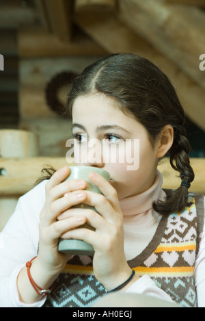 Ragazza adolescente di bere bevande calde, guardando lontano Foto Stock