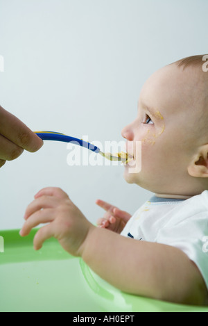 Baby essendo alimentato con cucchiaio, vista laterale Foto Stock