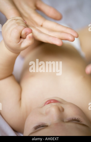 Il Bambino giacente sul retro, tenendo adulto del dito Foto Stock